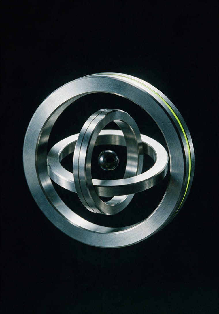 A machined three-axis gyroscope of nested white metal rings, on black