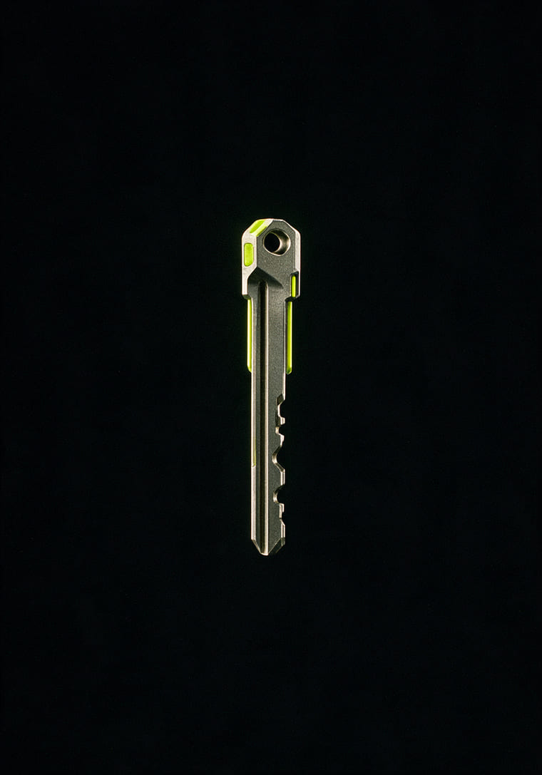 A machined titanium key blank with a lime inlay, on black
